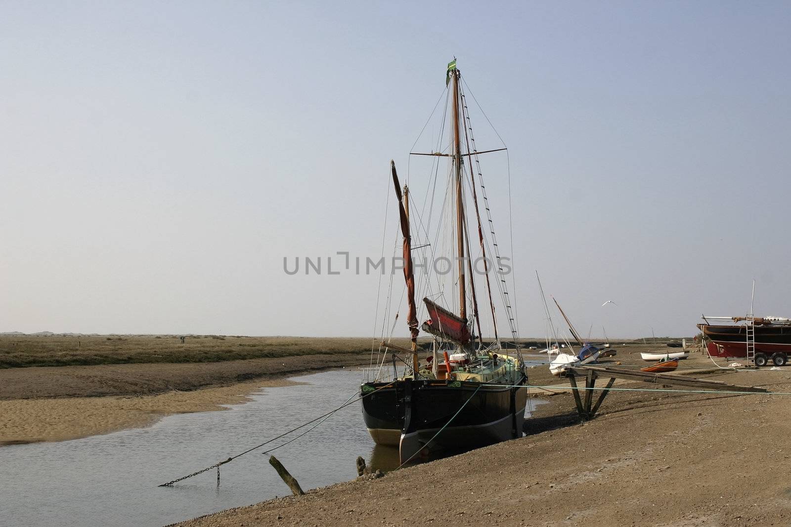 small ship with masts waiting for the tide to come into the estuary