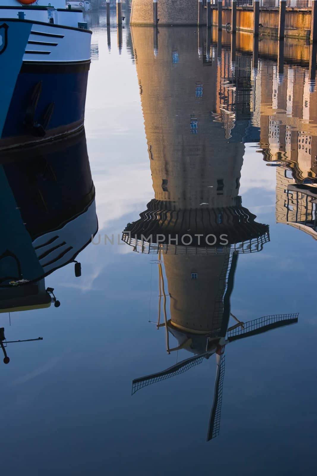 Reflection of ship and mill at blue and gold sunrise - vertical image