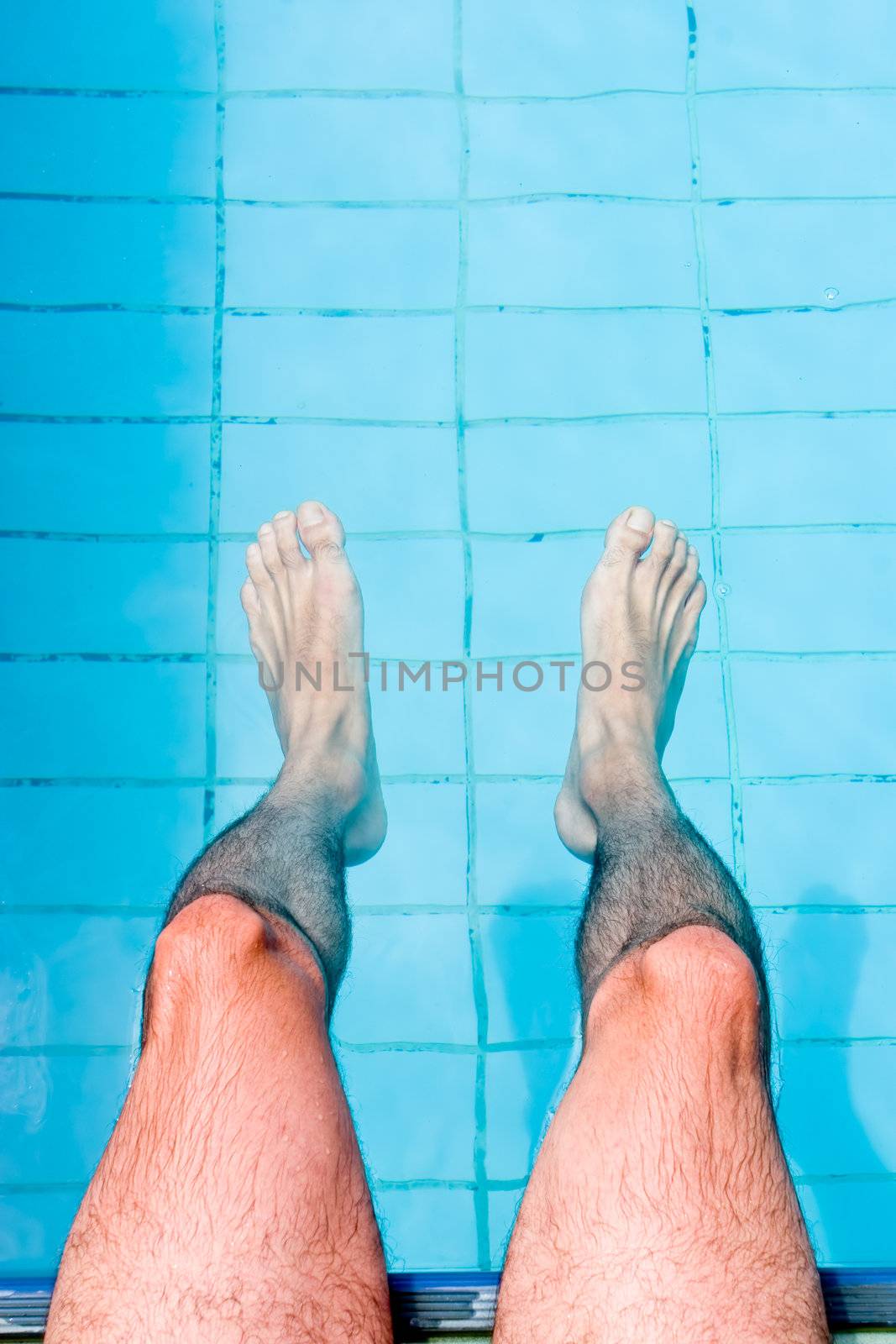 Male legs on water, by the pool.