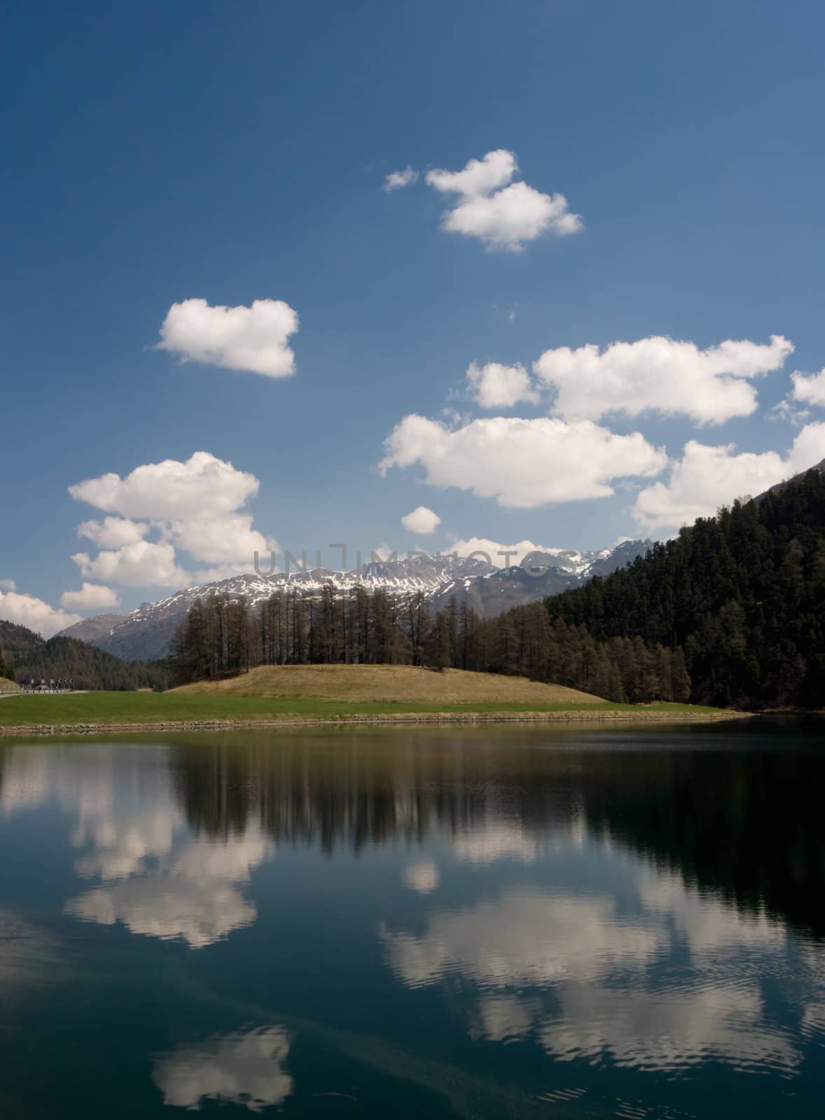 Lake reflection on a beautiful spring day, in the Swiss Alps. Silvaplana / Saint Moritz, Switzerland.