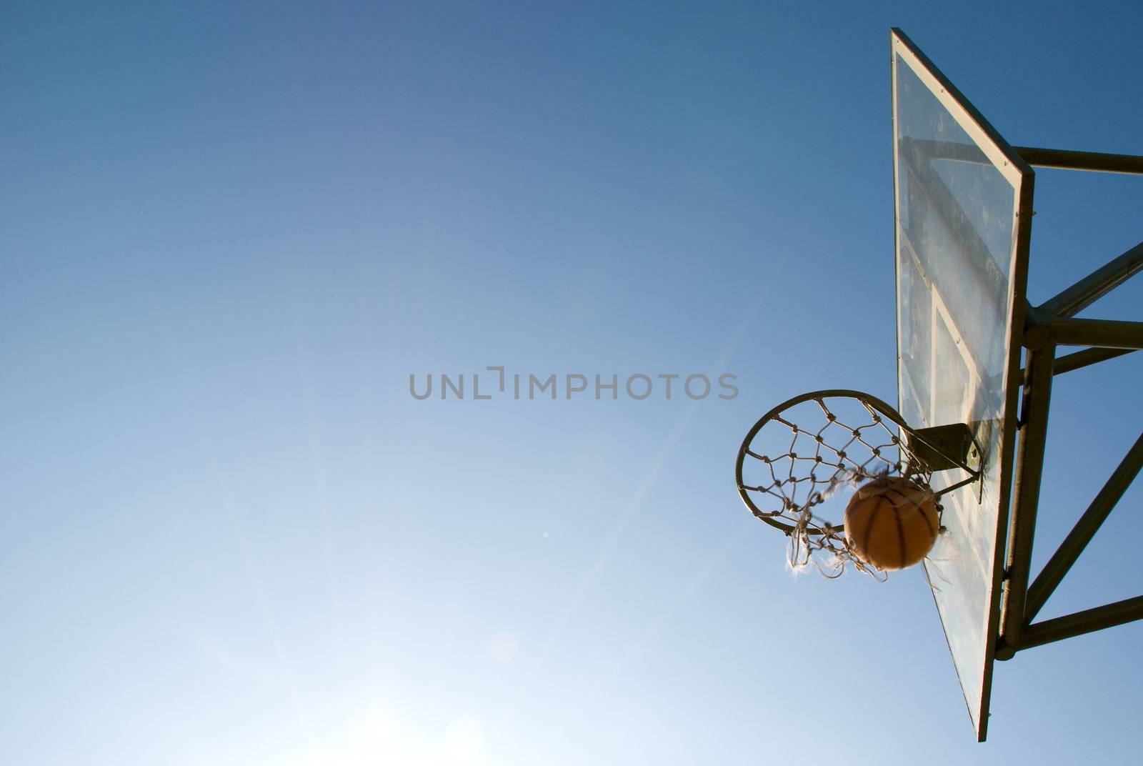 Basketball dropping into the net in a basketball game on an open court at sunset