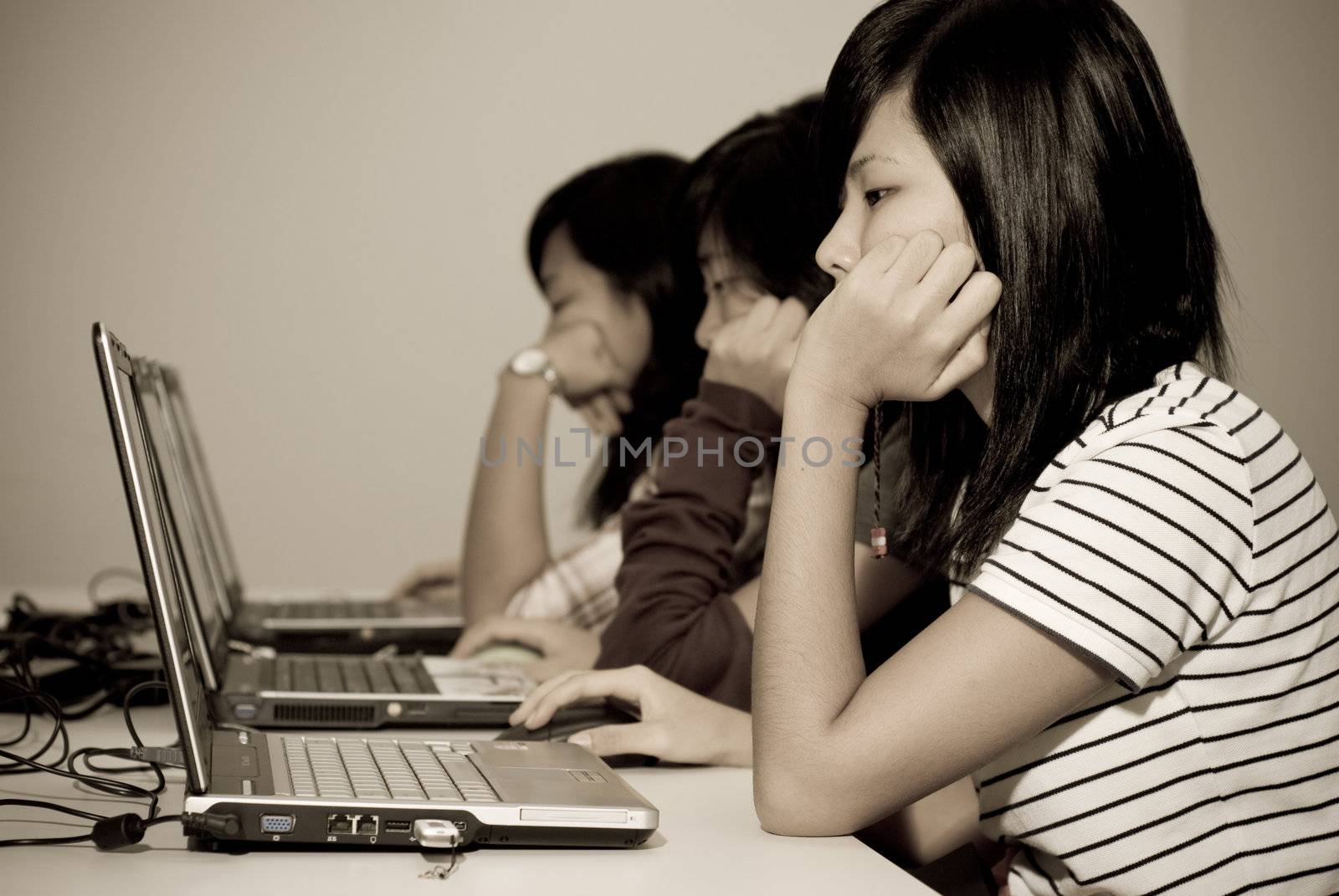 A trio of teenager girls engrossed in the content on their networked laptop PCs