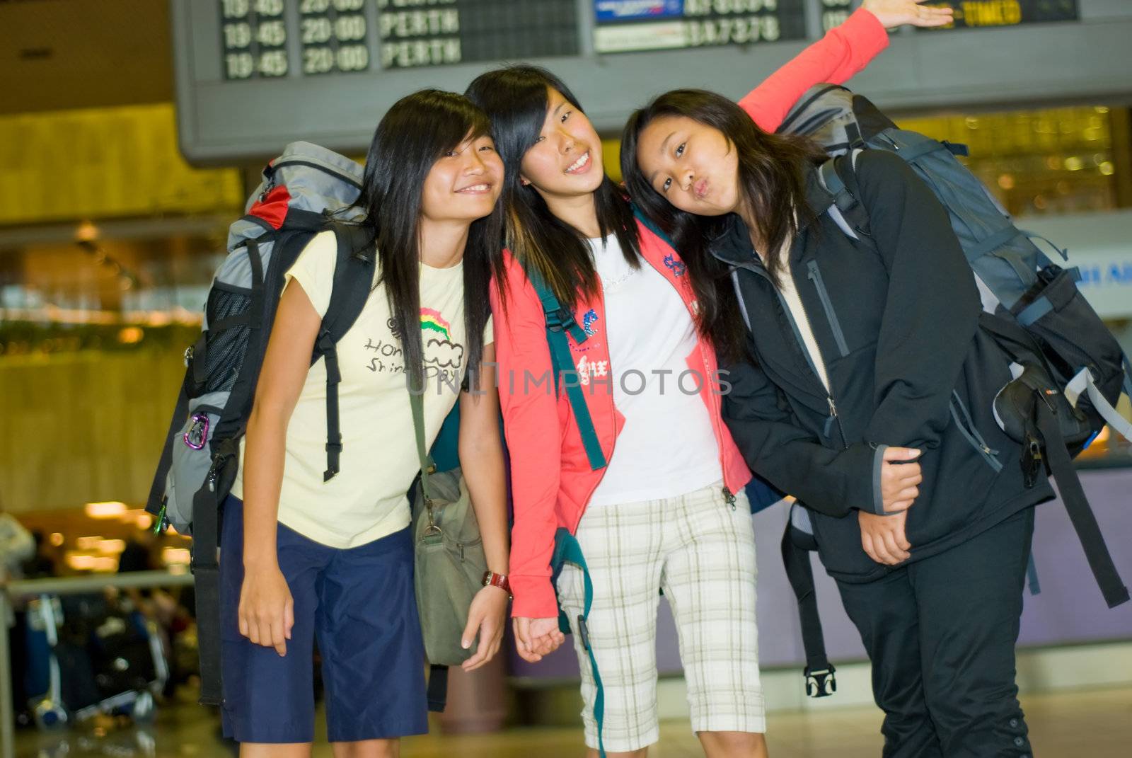 Three girls posing for a farewell group shot at the airport before departing for a holiday