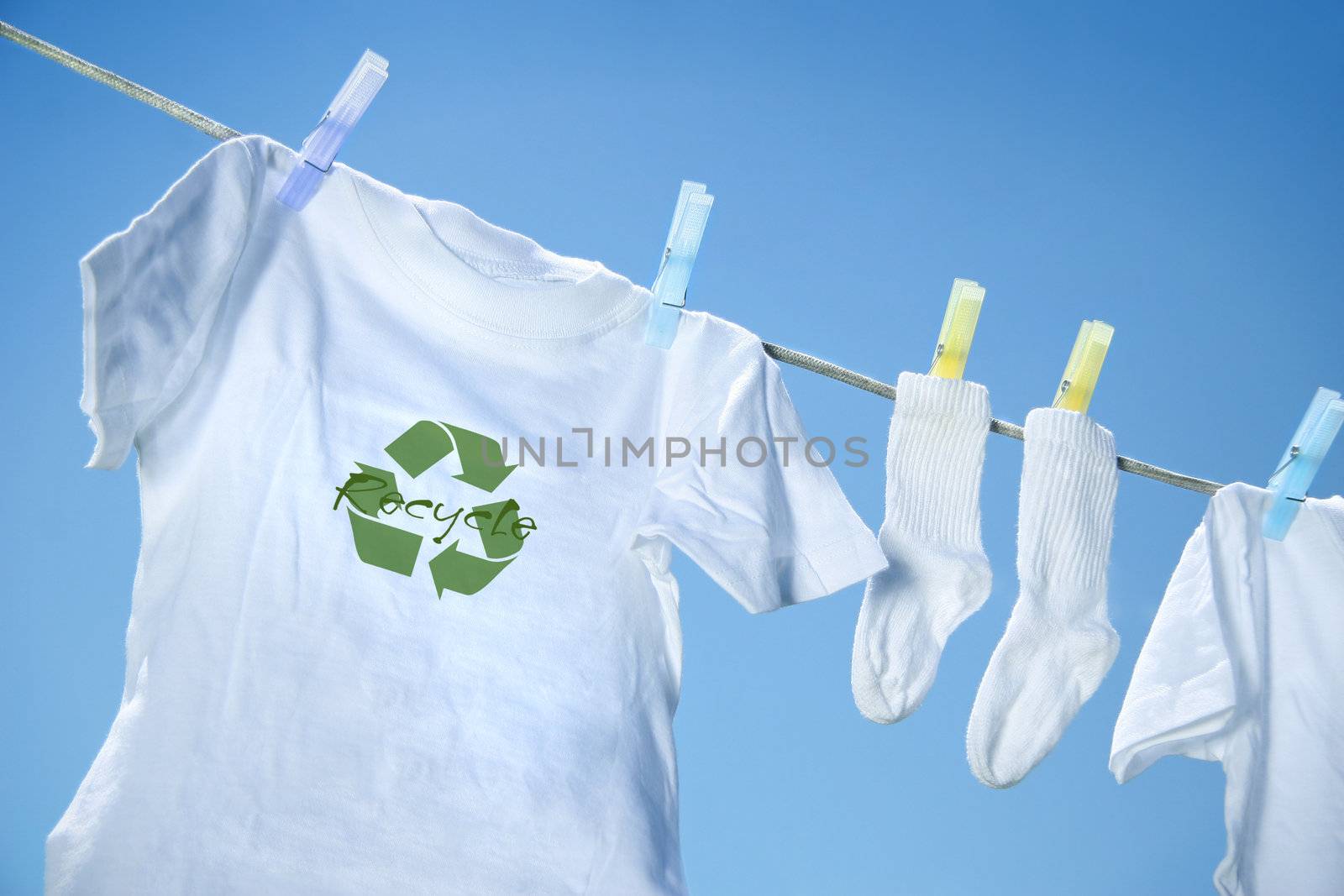 T-shirt with recycle logo drying on clothesline on a  summer day by Sandralise