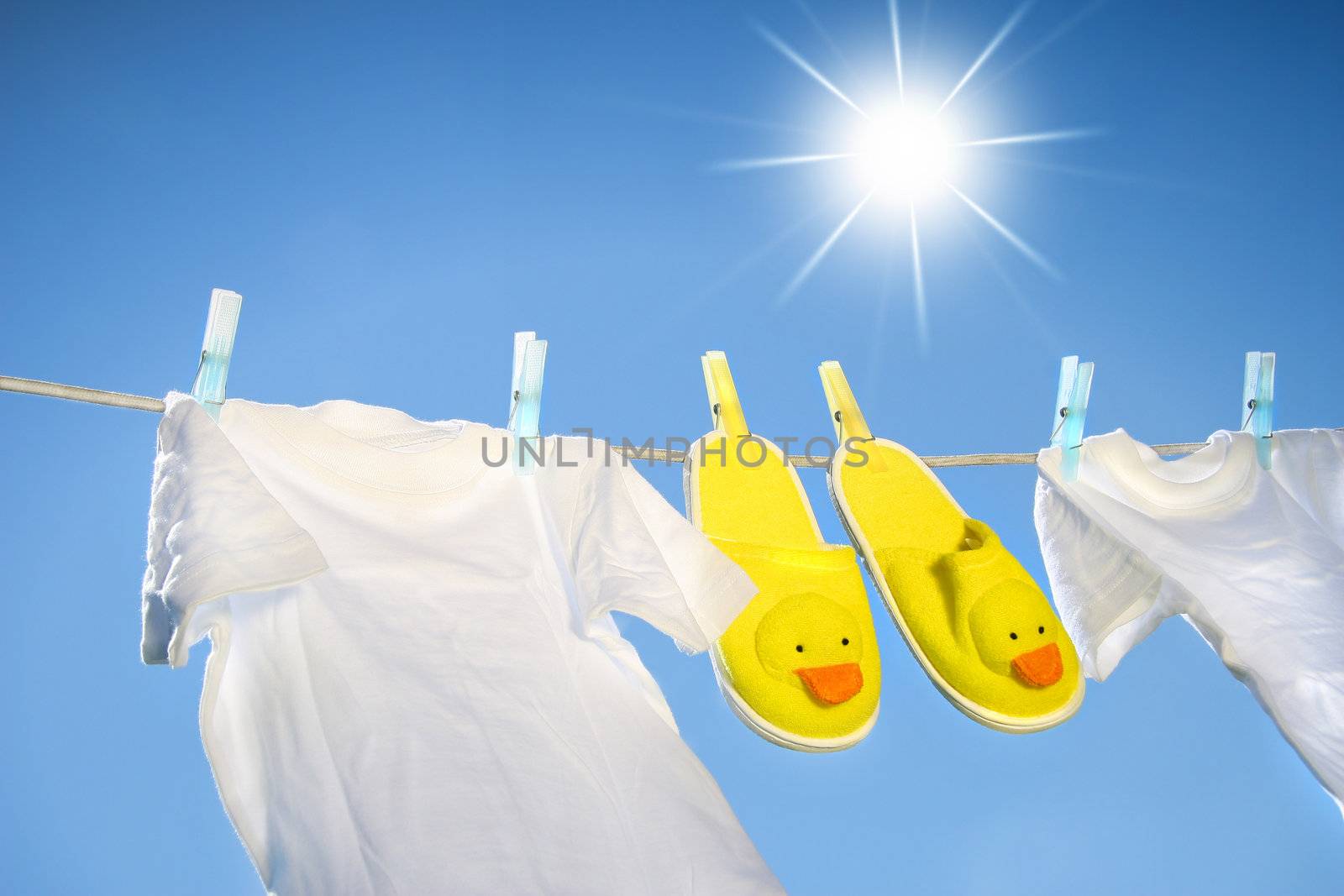 White t-shirts and slippers on the clothesline on a sunny day