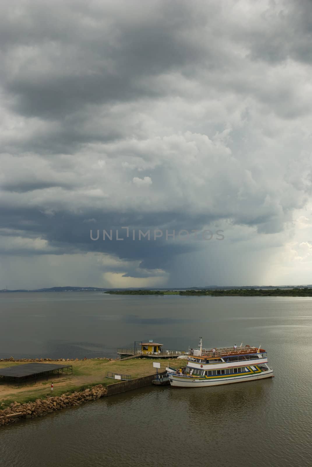 Vertical seascape shot of a boat in the show with huge storm looming in the horizon. 2/3 copy space.