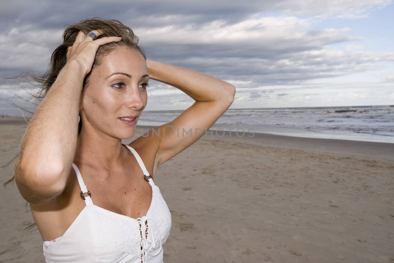 Beautiful young girl in the sand (late afternoon), with cloudy sky.