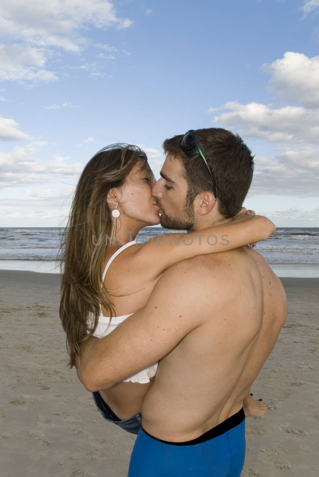 Young healthy couple kissing in the beach. 