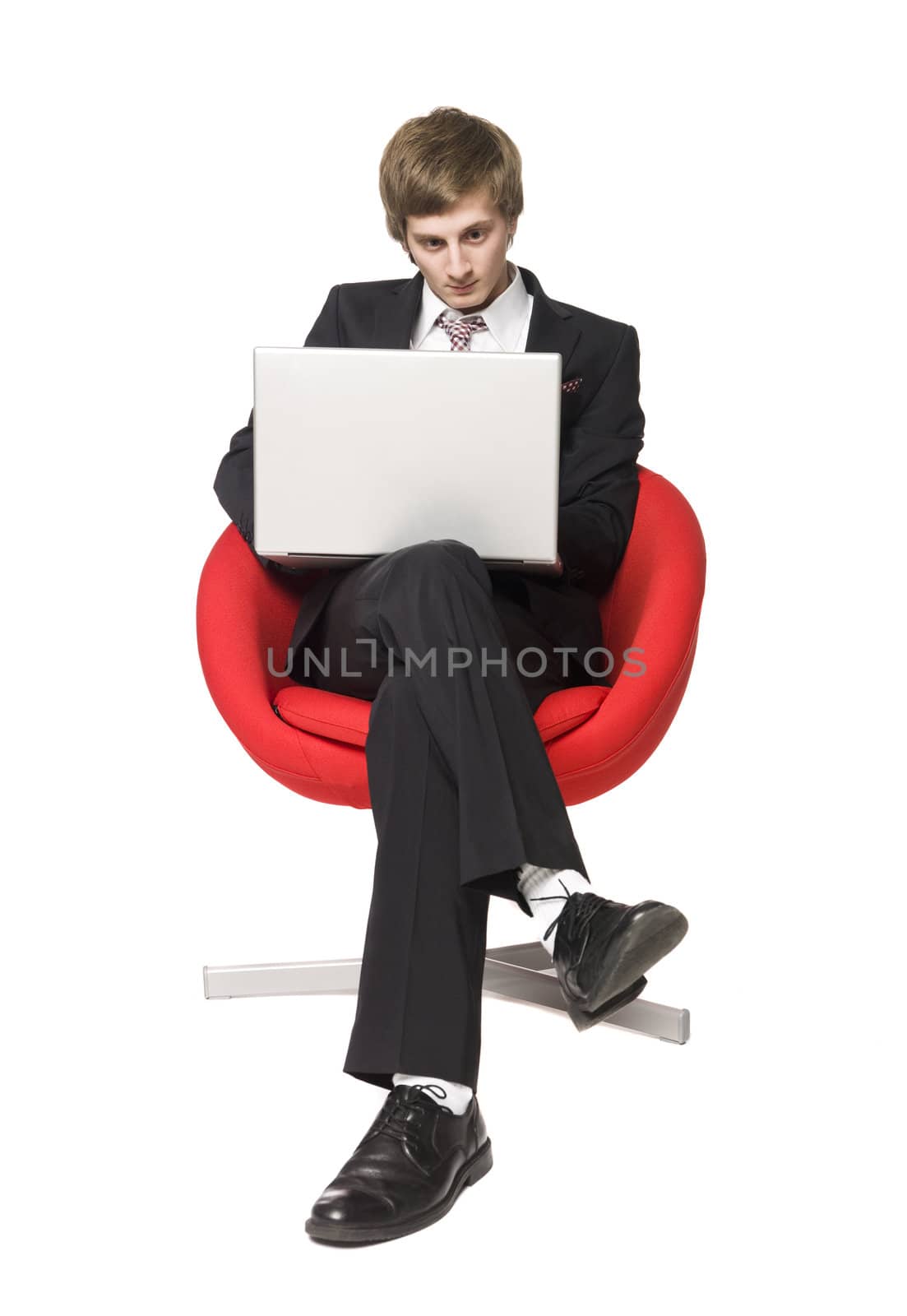 A boy in a red armchair with a laptop