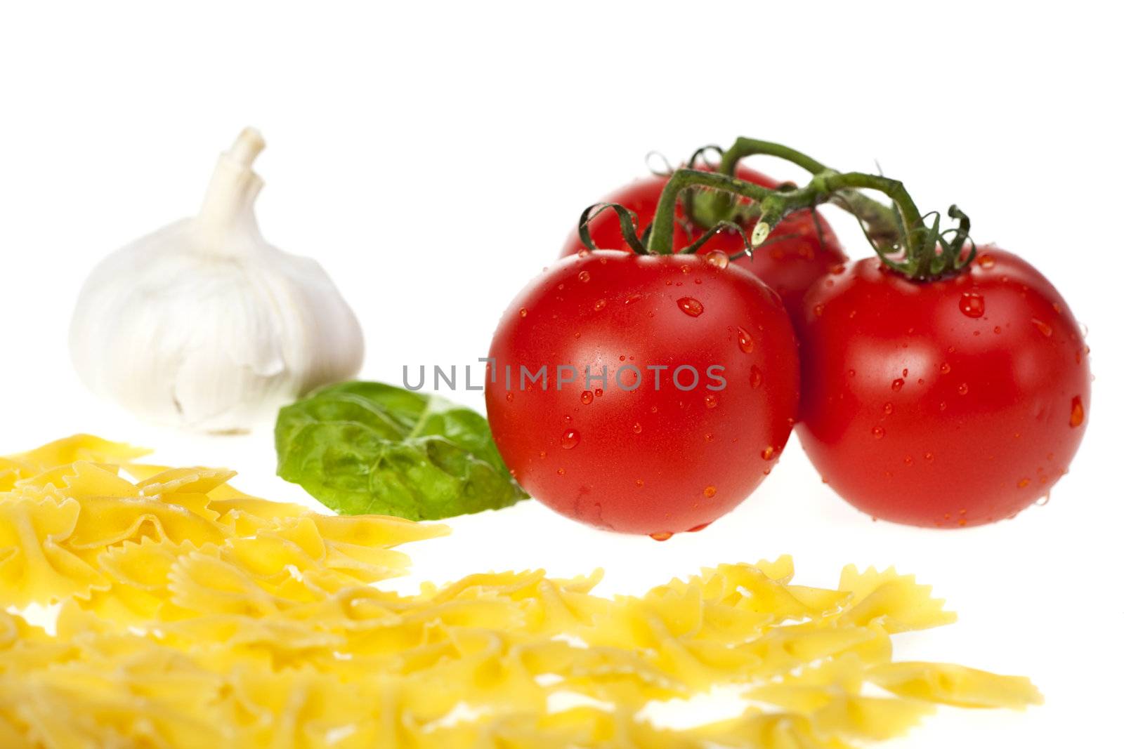 farfalle pasta, tomatoes, garlic and a basil leaf