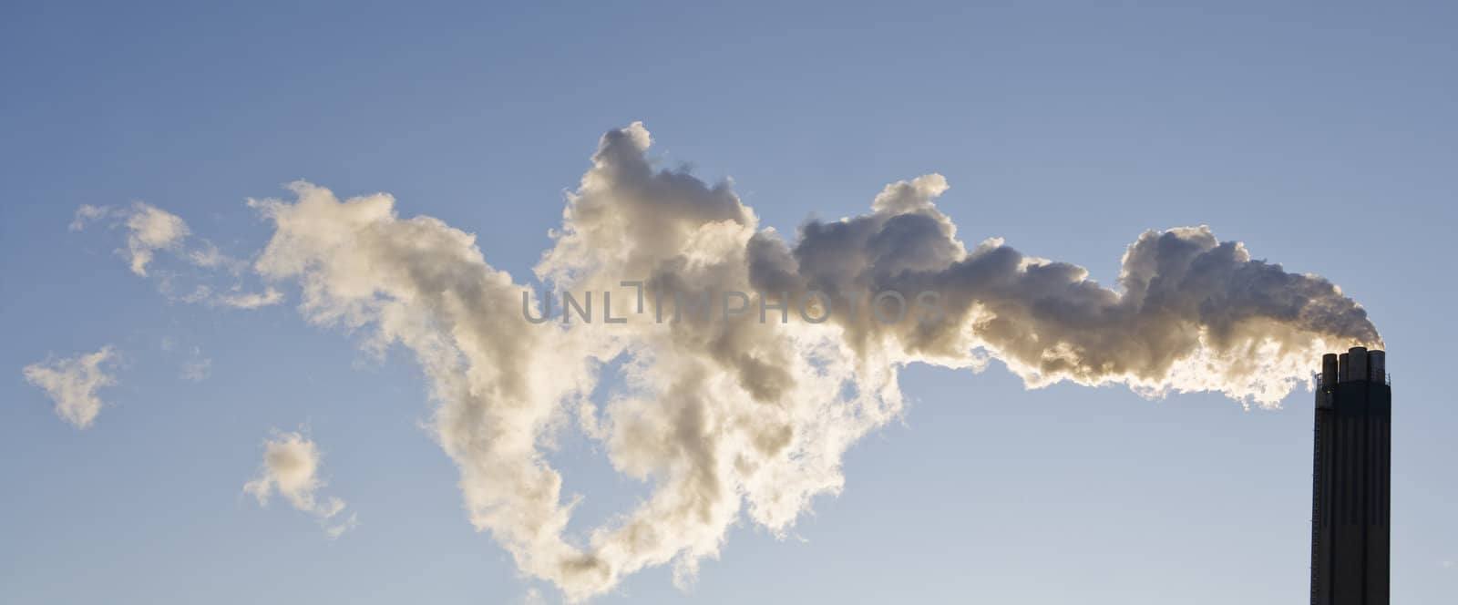 Smoking chimney against a blue sky by gemenacom