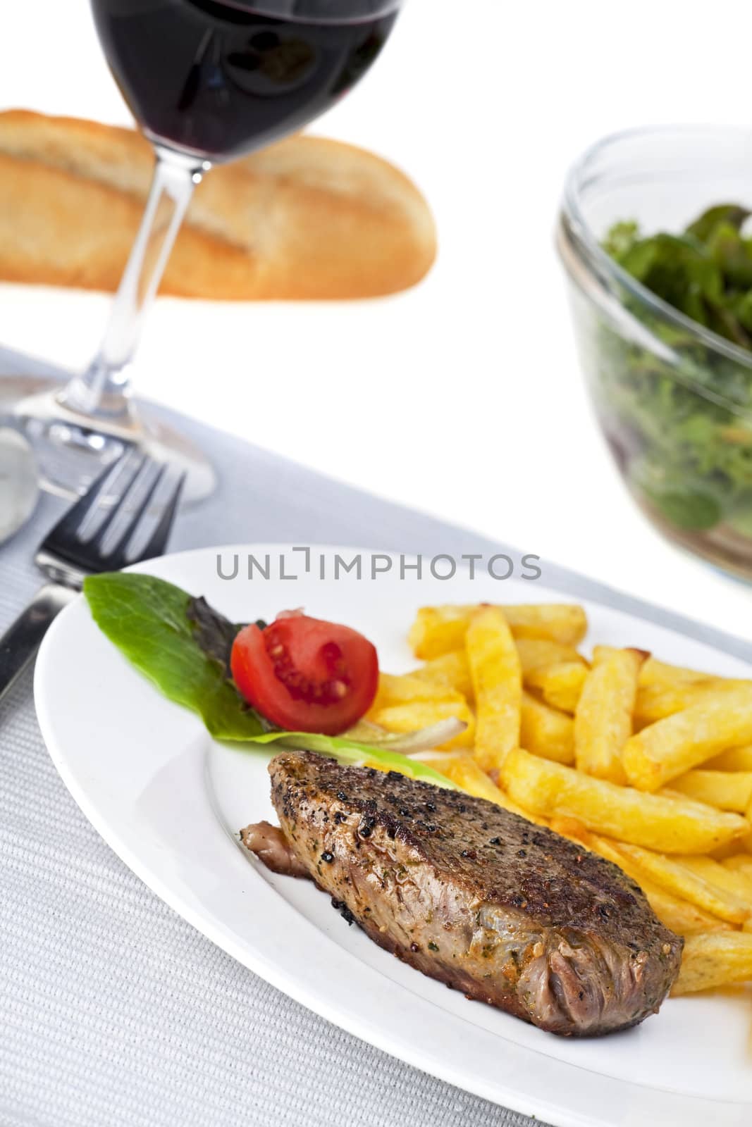 closeup of a beef steak with french fries on a white background