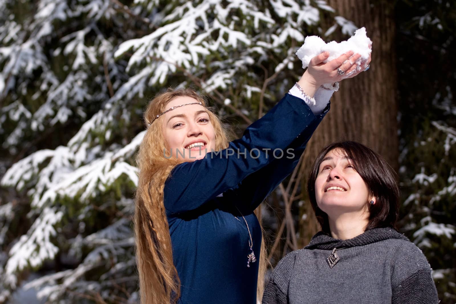 Two ladies in medieval dresses in winter forest

