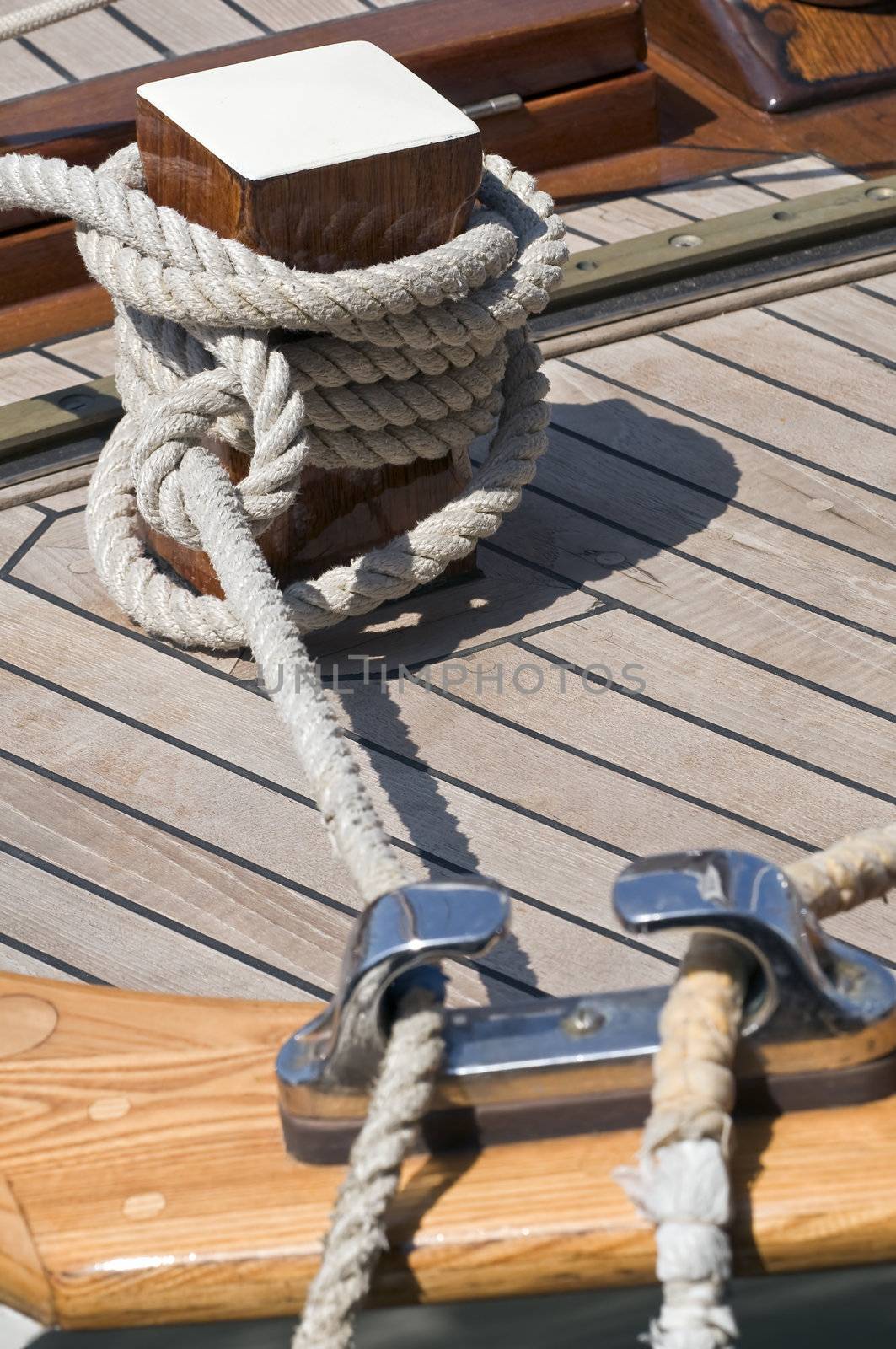 Detail of a wooden boat with rope tied up on a bitt