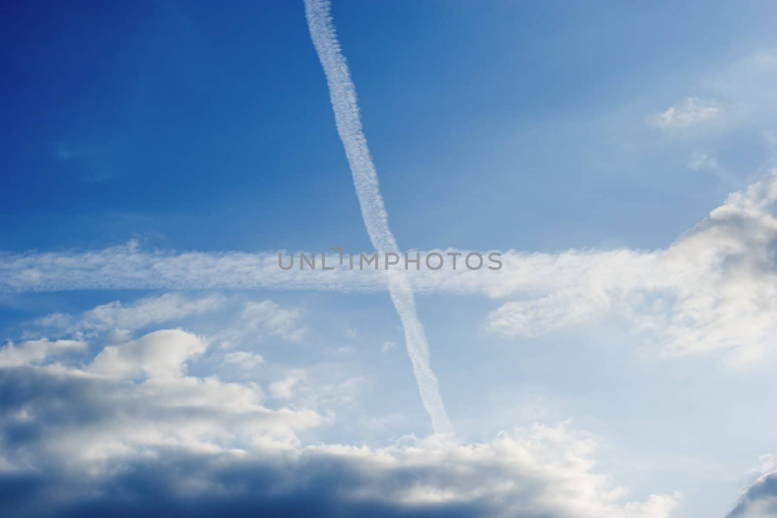 Cross in blue sky. Two airplanes trail.