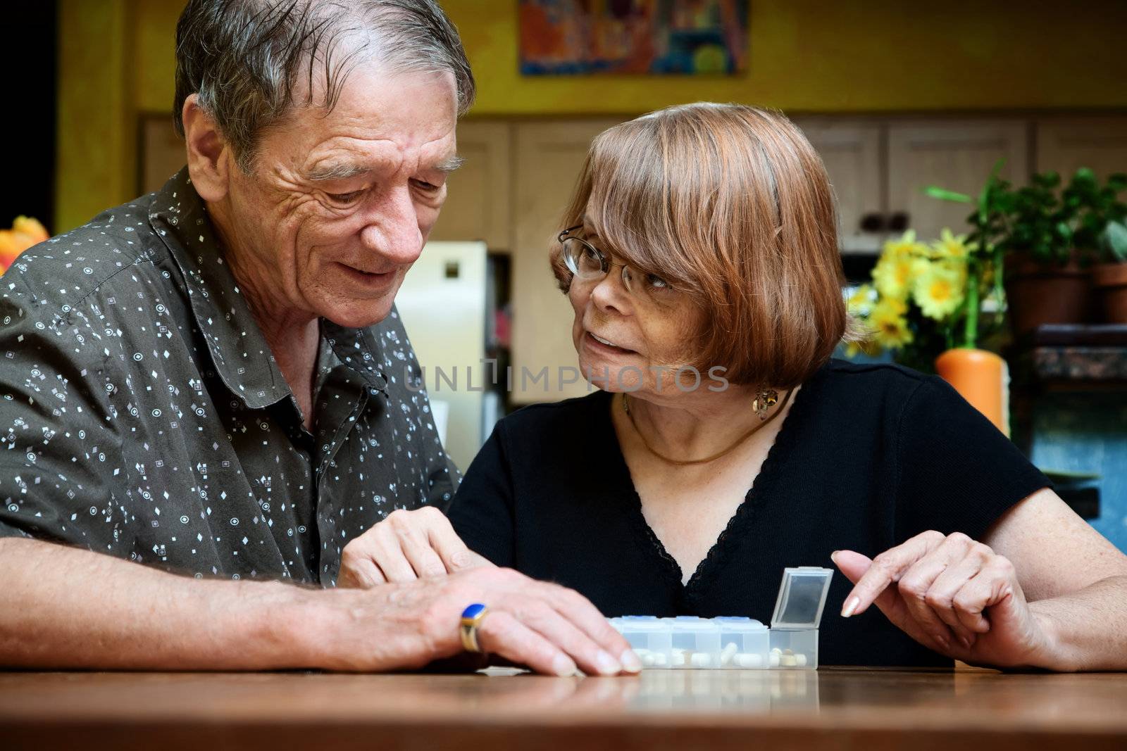 Senior couple at table with daily health supplements