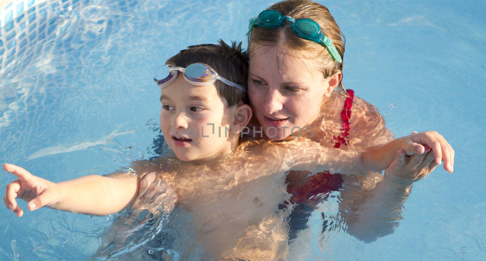 Mother and son in the swimming pool cozyly together spending their time.