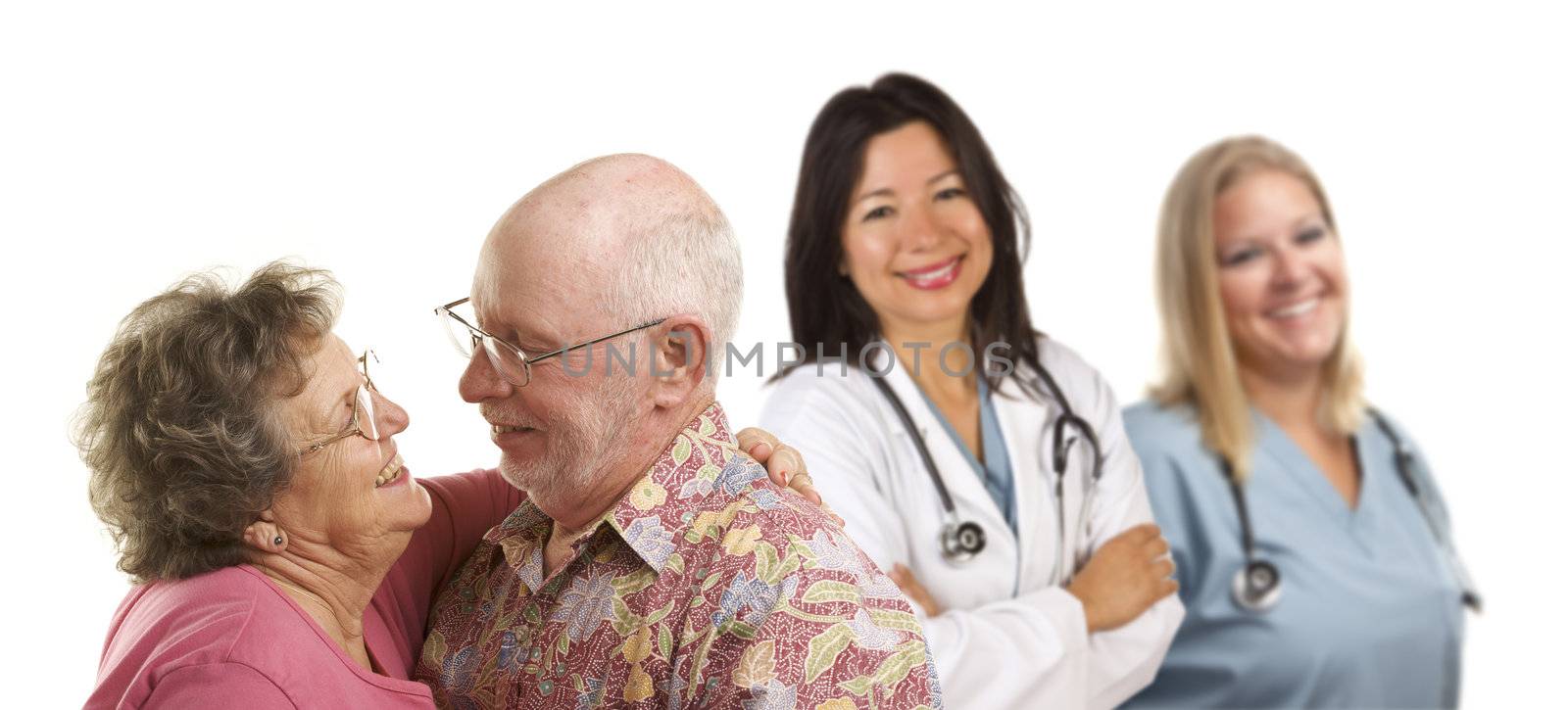 Happy Loving Senior Couple with Smiling Medical Doctors or Nurses Behind Isolated on a White Background.