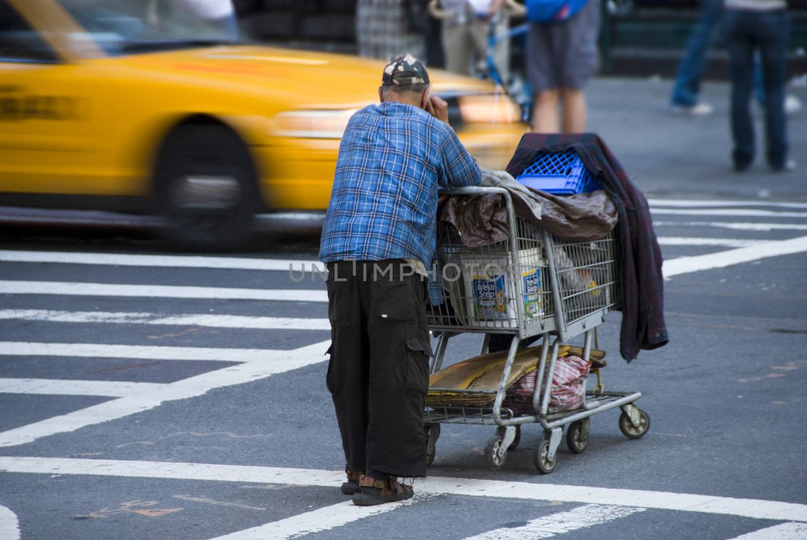 A homeless man awaiting his turn to cross the street