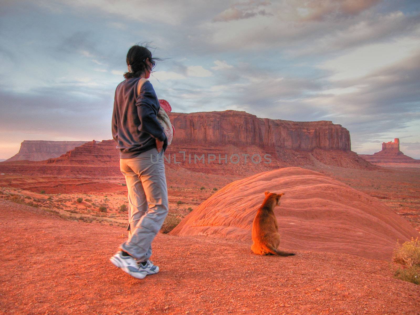A girl and her dog watching sunset in Monument Valley