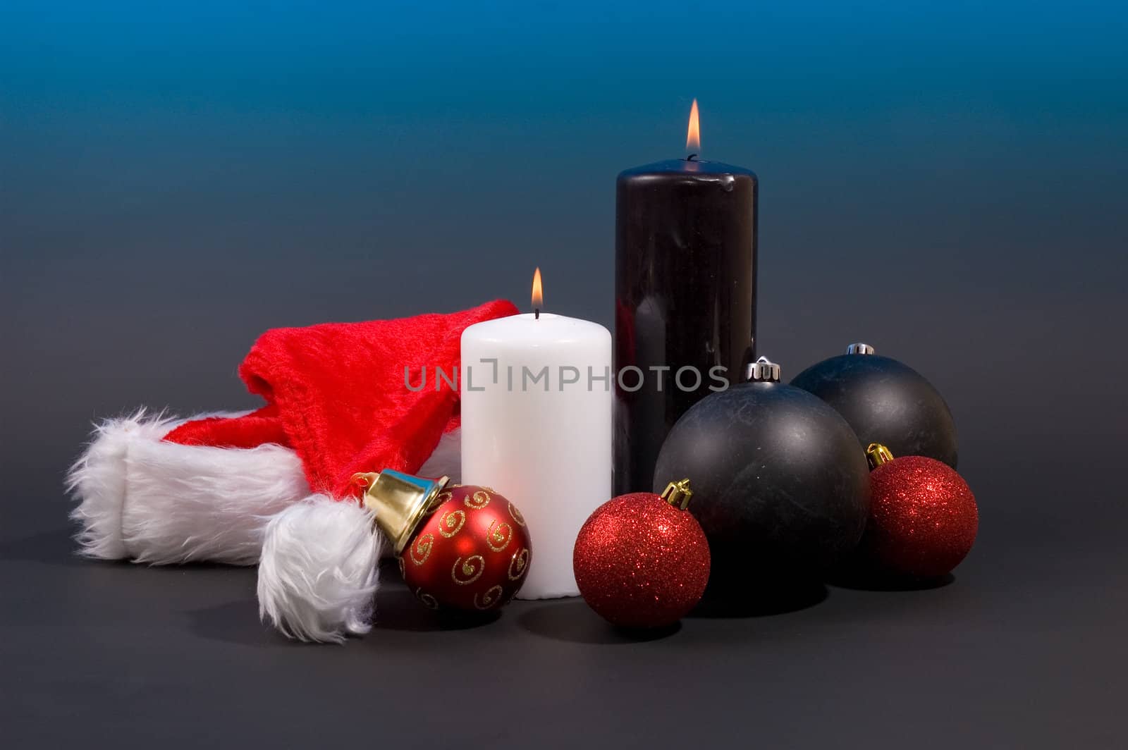 burning candles with christmas balls and hat