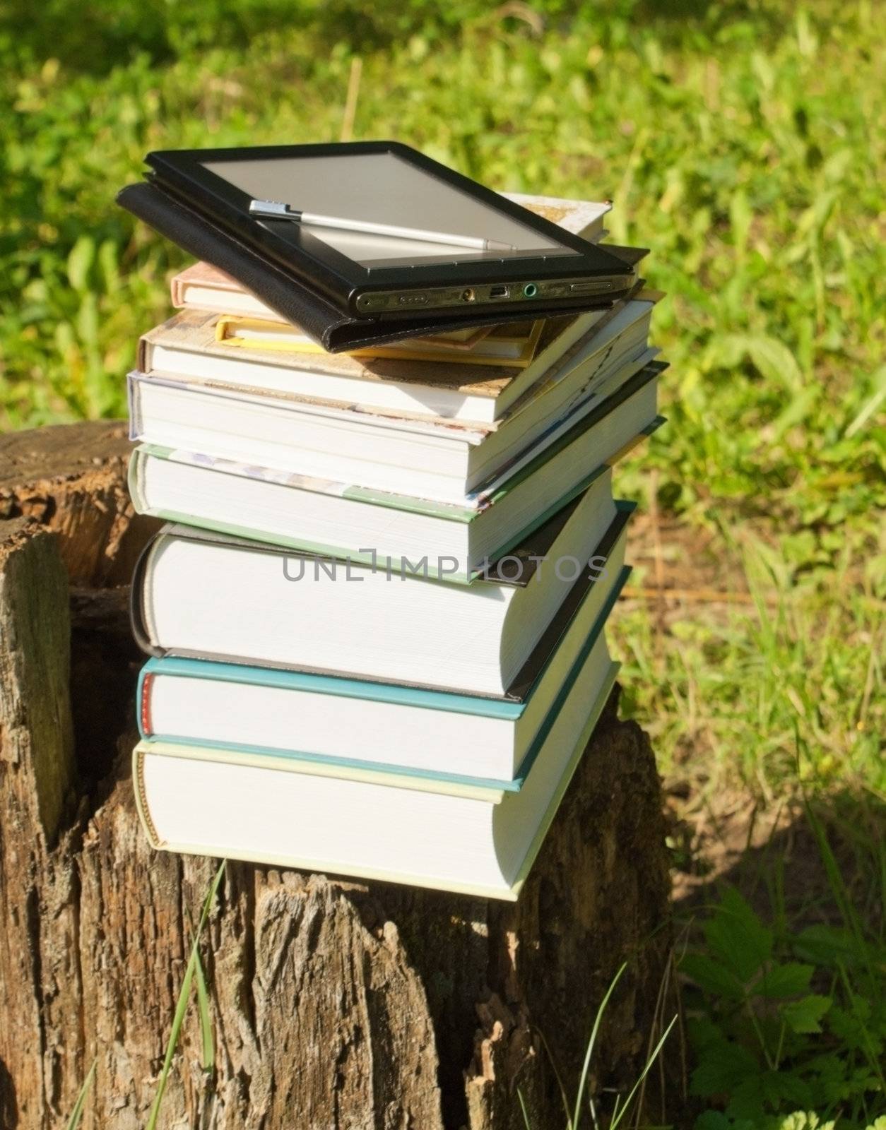 Stack of colorful books and electronic book reader