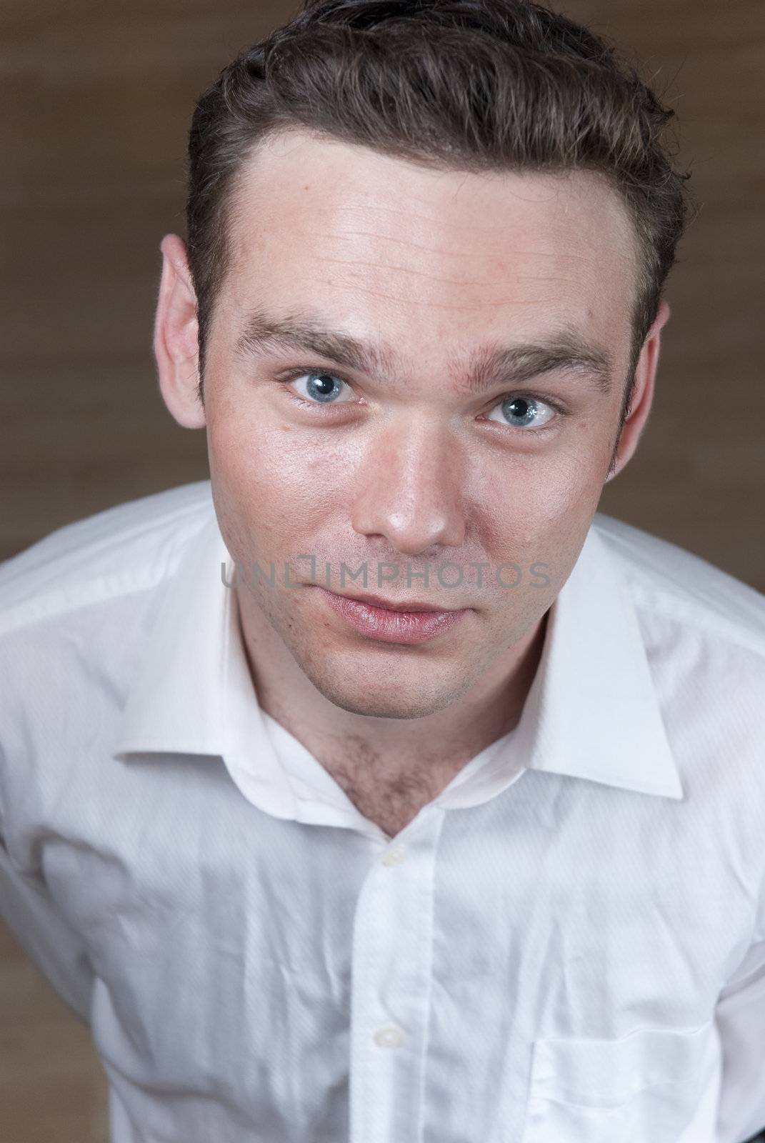 High angle headshot of young white man with wooden board floor in the background.