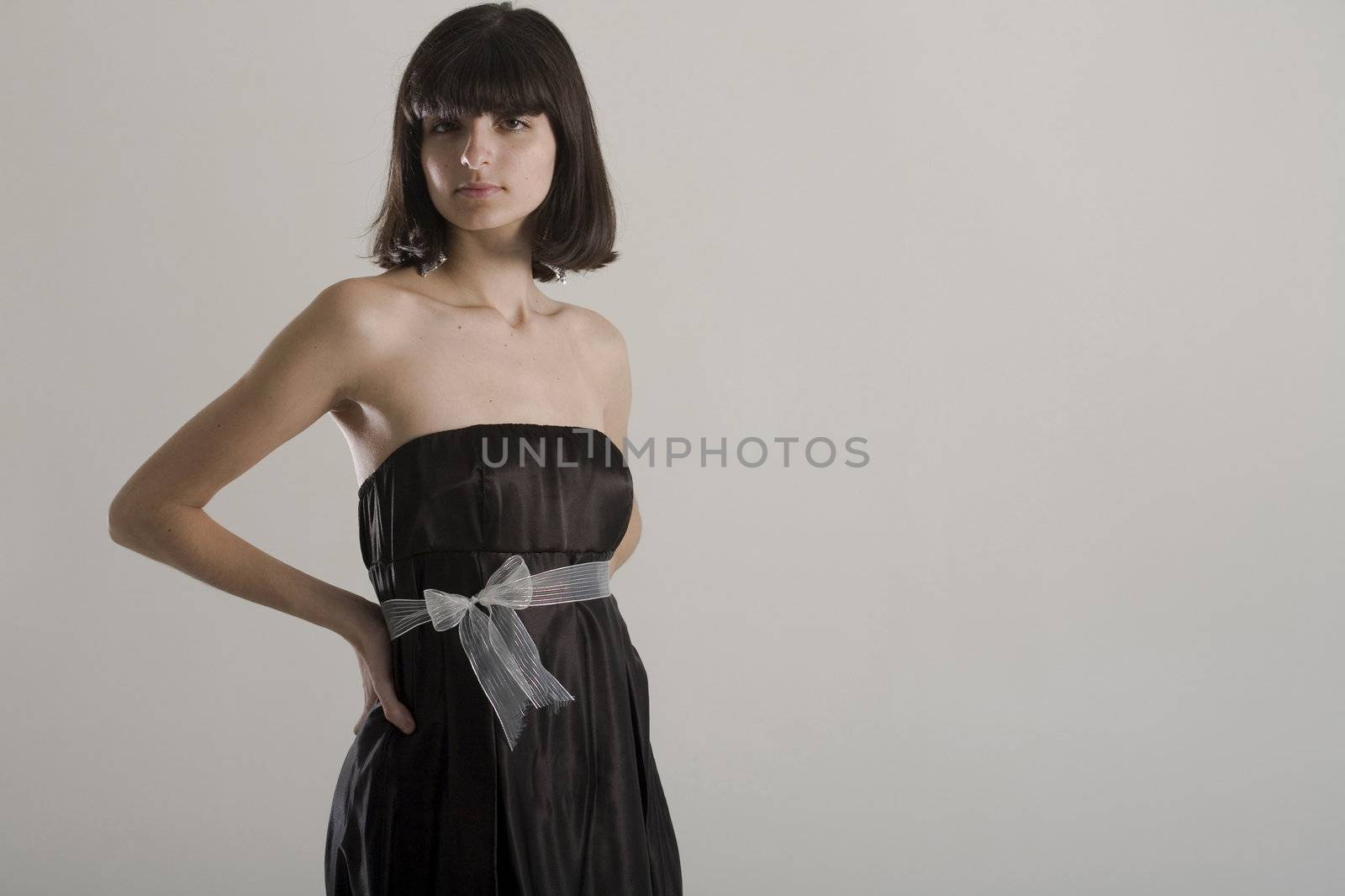 An 18 year old exotic brazilian model, with short dark hair, a young looking face and a skinny body. This was shot in a studio and she's weariing a black, strapless dress. Plenty of copyspace in the image.