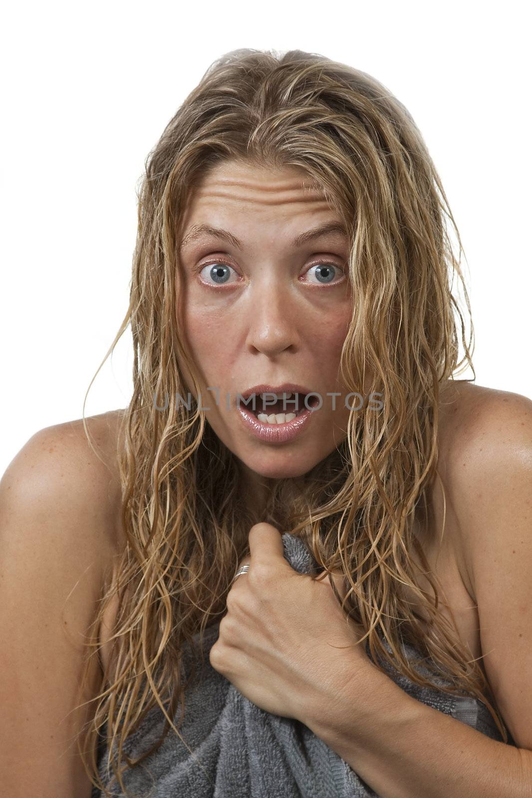 Blond woman with curly hair is surprised and scared while getting out of the shower, grabs her towel. Maybe it's an intruder, or her voyeurist neighbour through the window.