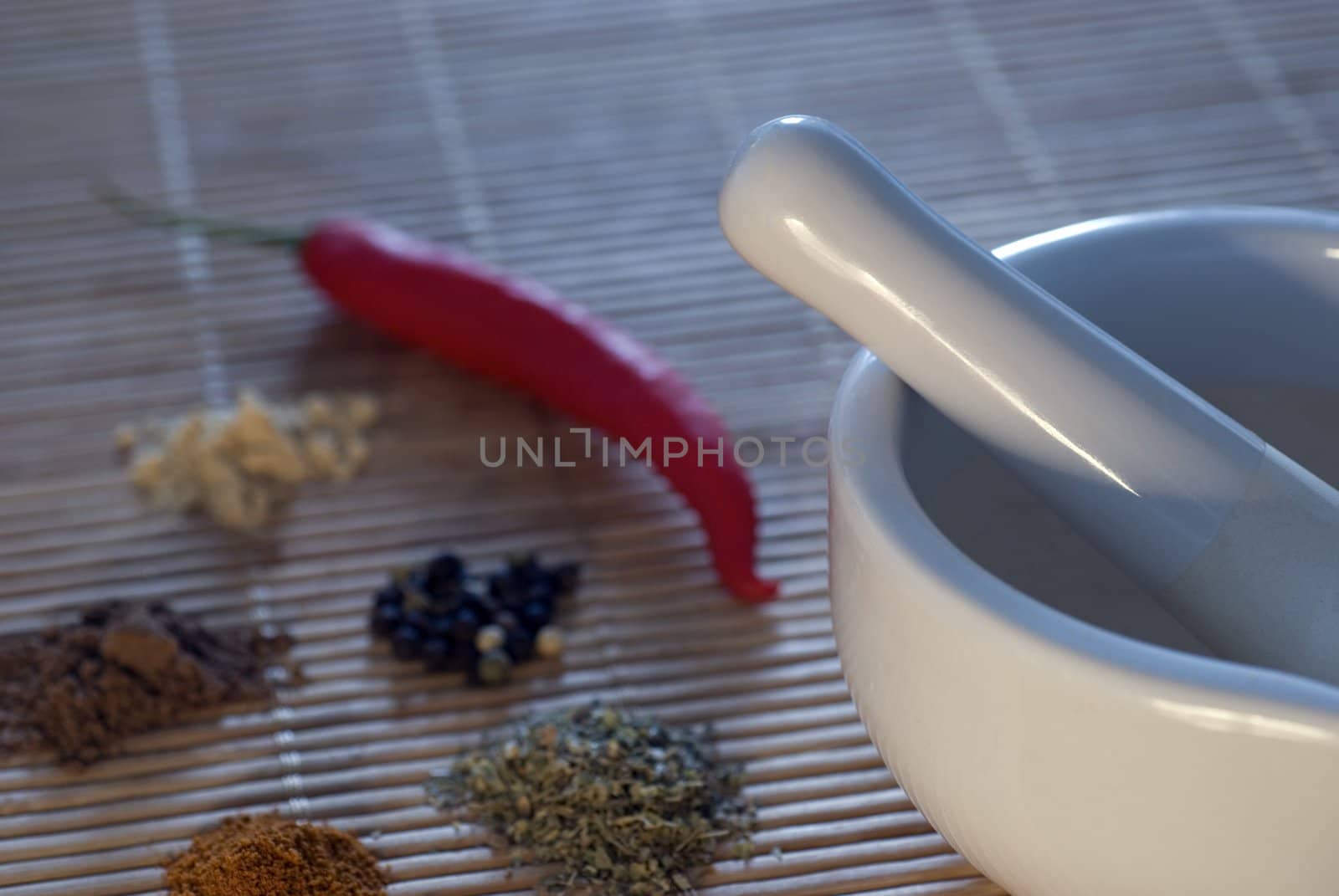 a white pestle and mortar with a selection of spices, narrow depth of field