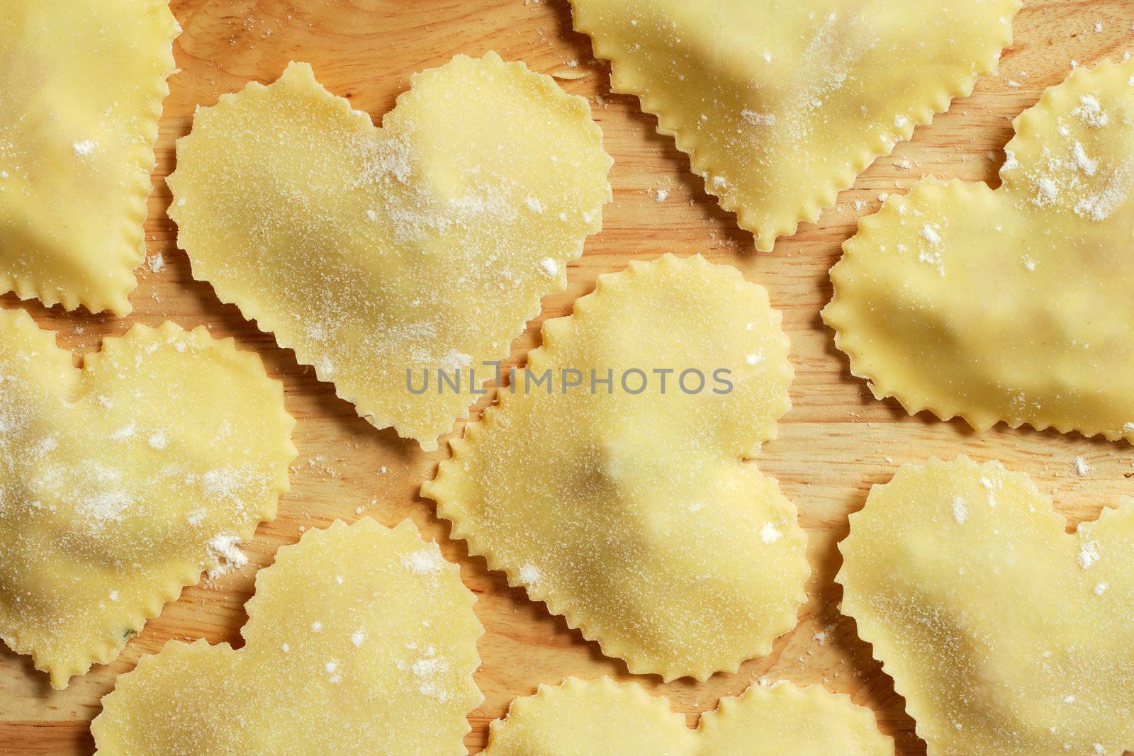Heart-shaped homemade pasta sitting on a wooden countertop.
