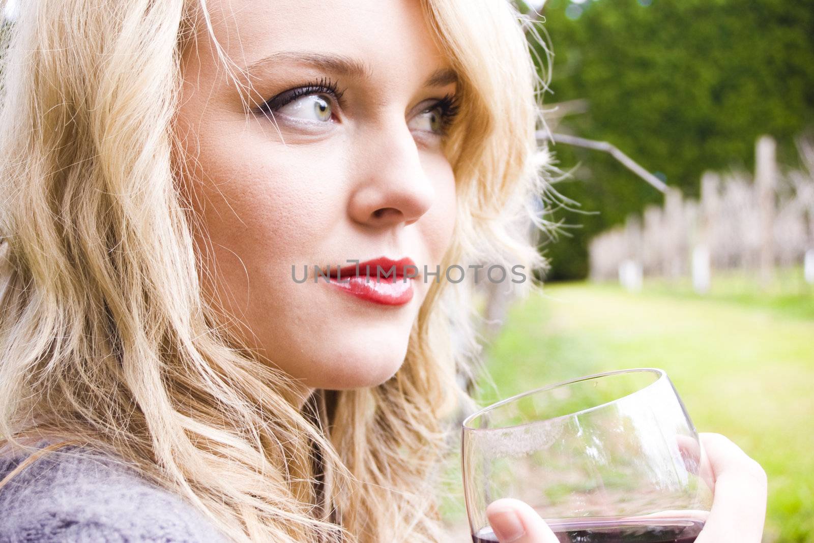 Young pretty girl in a vineyard drinking red wine