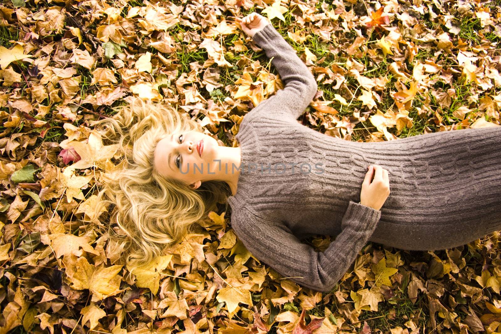 Young girl lying in the Autumn fall leaves