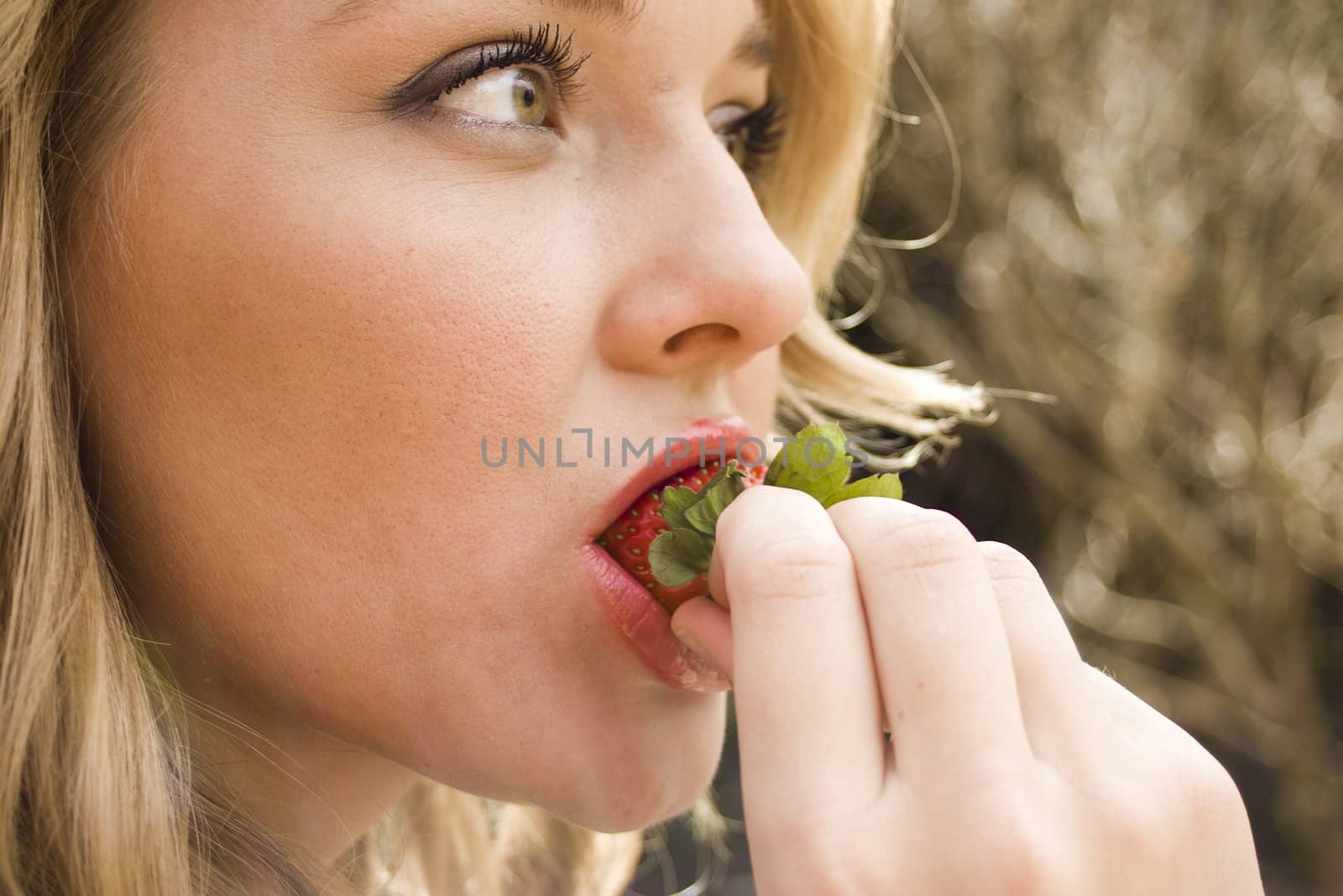 Close-up of a young woman biting a strawberry