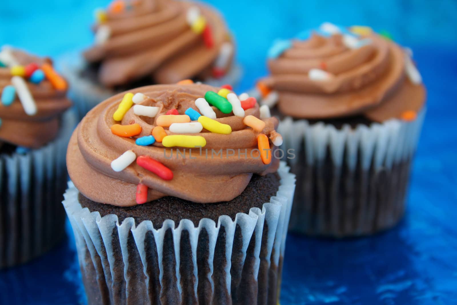 chocolate frosted cupcakes on a metallic blue background