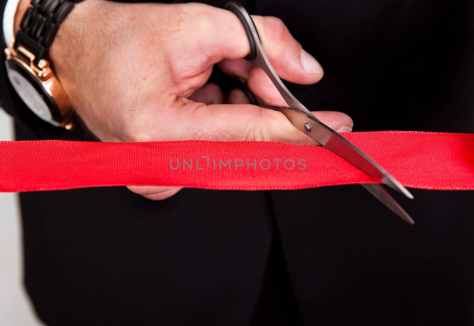 Businessman cutting a red tape against white background