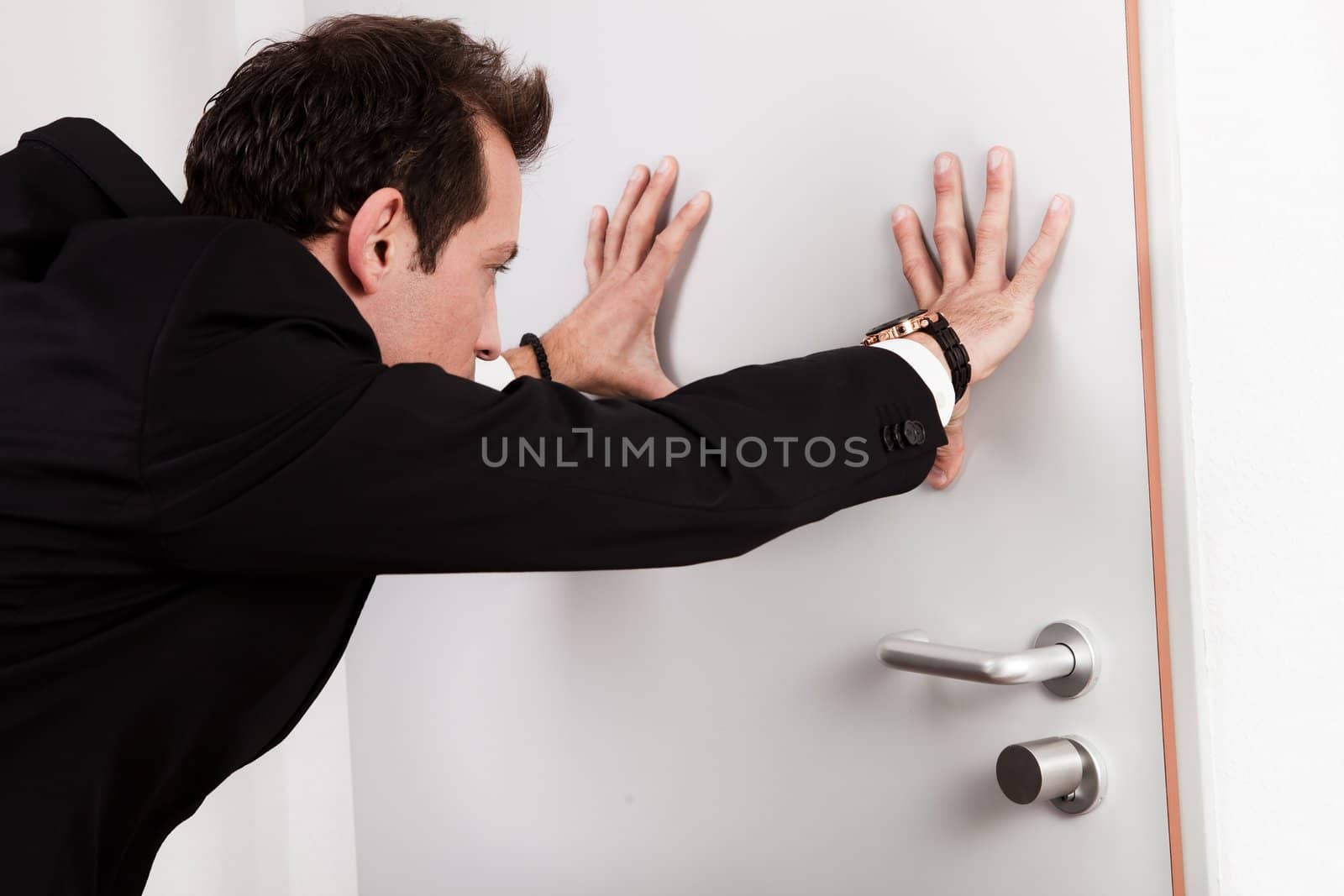 Businessman pushing the door to prevent people entering room