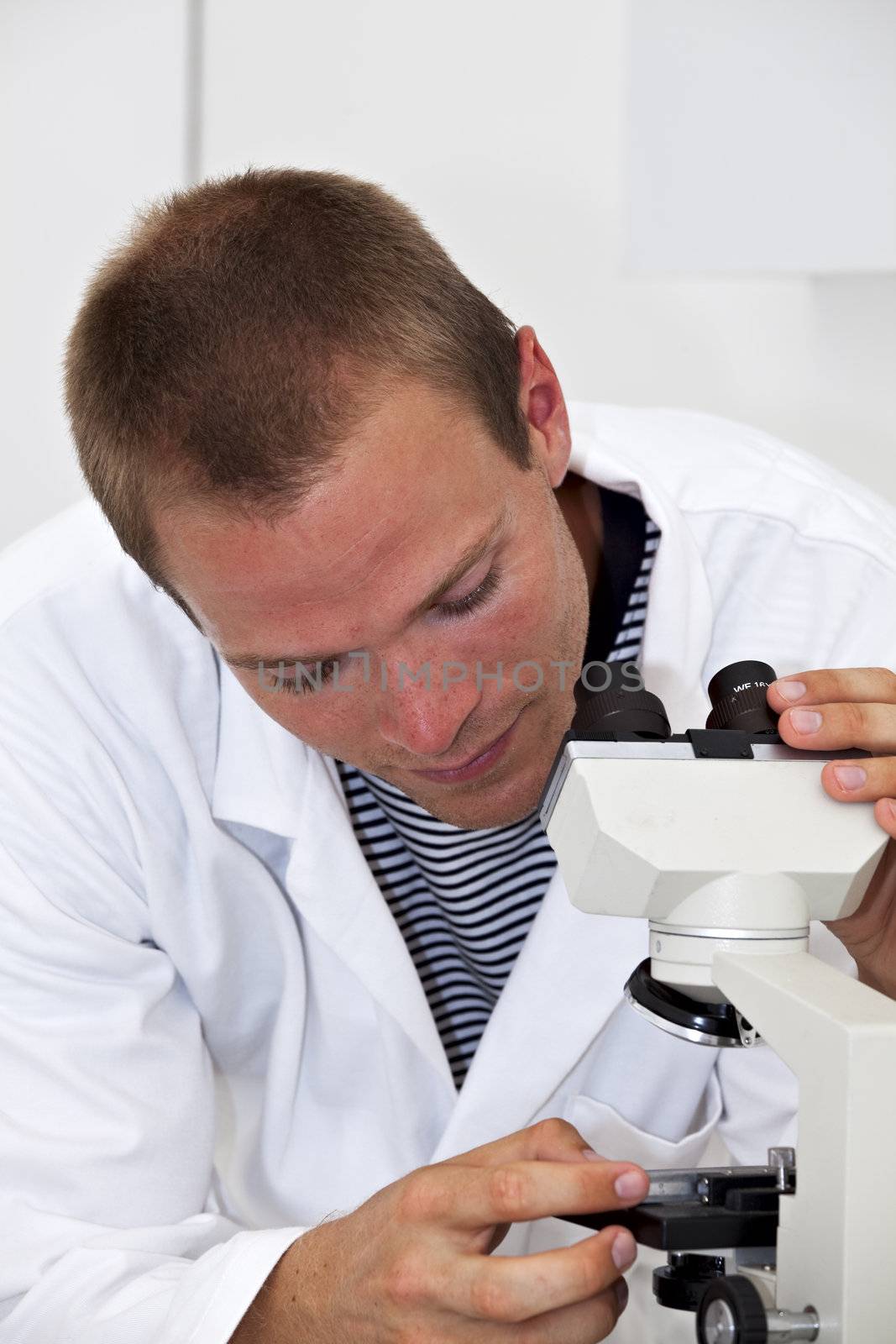 young lab technician fiddling with a microscope