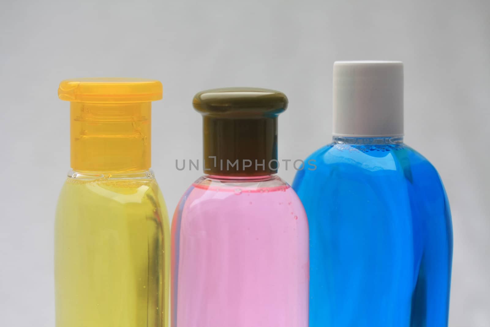 Close up of three shampoo bottles in yellow, pink and blue