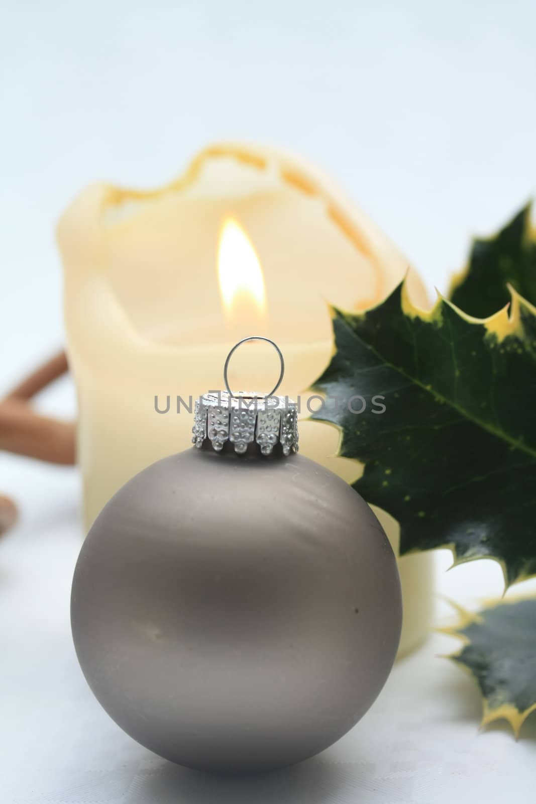 A grey christmas ornament with a burning candle on background