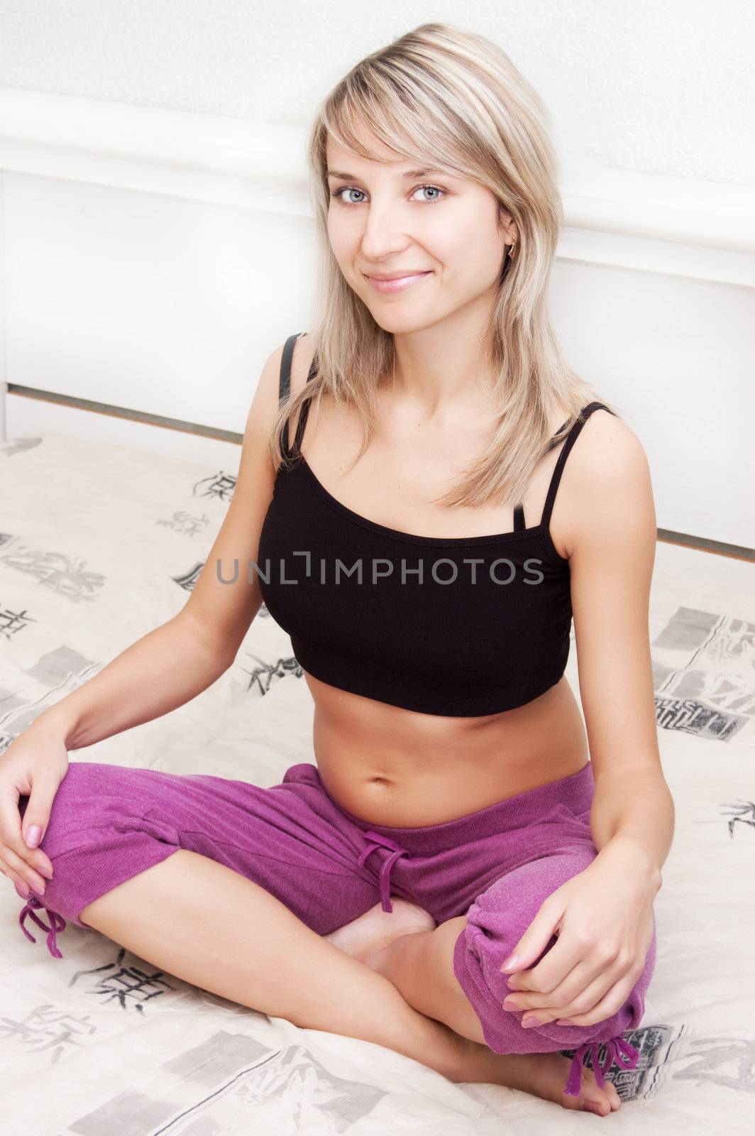 Beautiful young woman doing meditation on the bed