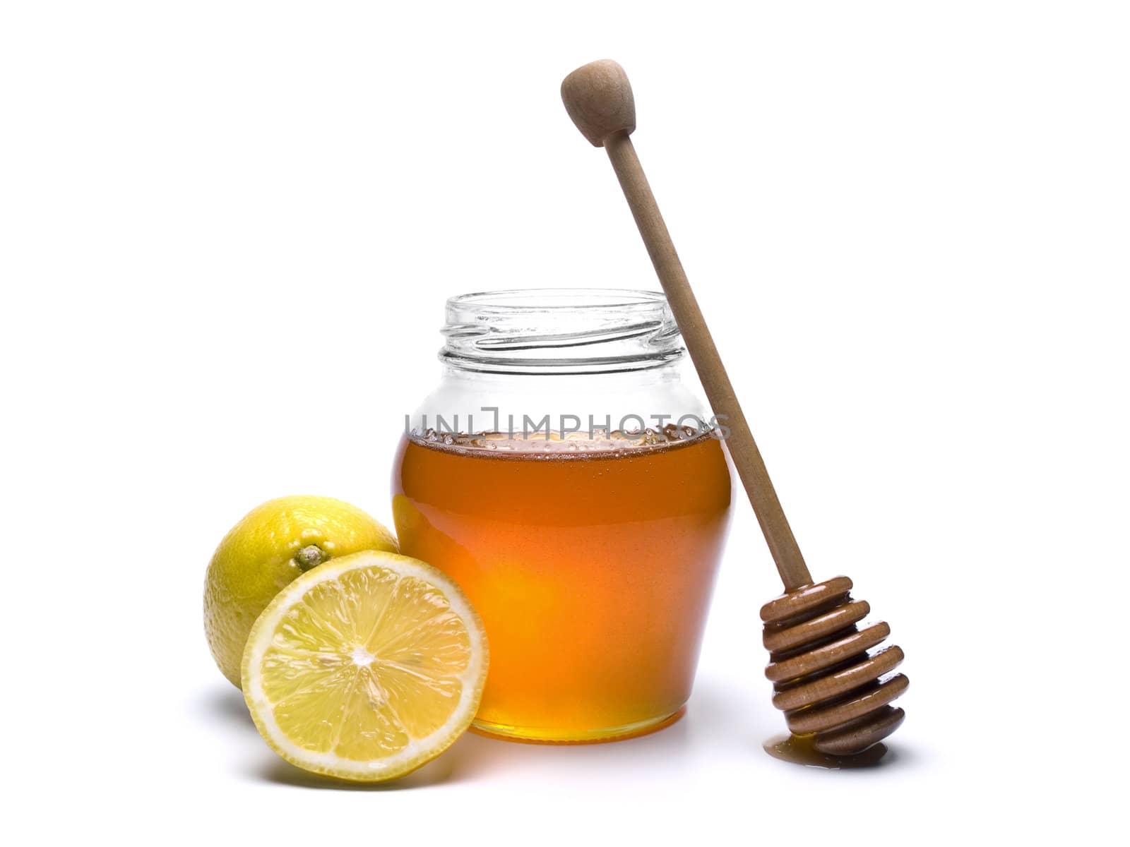 Jar of honey with a wooden drizzler and lemons. Isolated on white background.