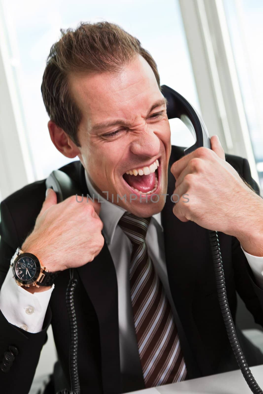 Stressed young businessman screaming on the phone