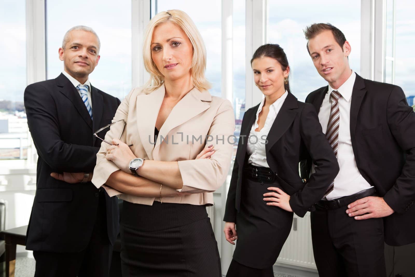 Businesswoman sitting in front. Three business colleagues working in background.