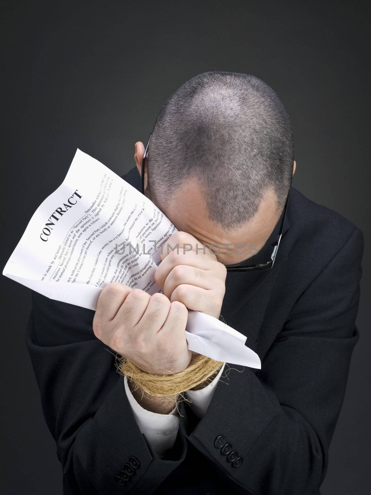 A man on a suit holds a contract on his tied hands.
