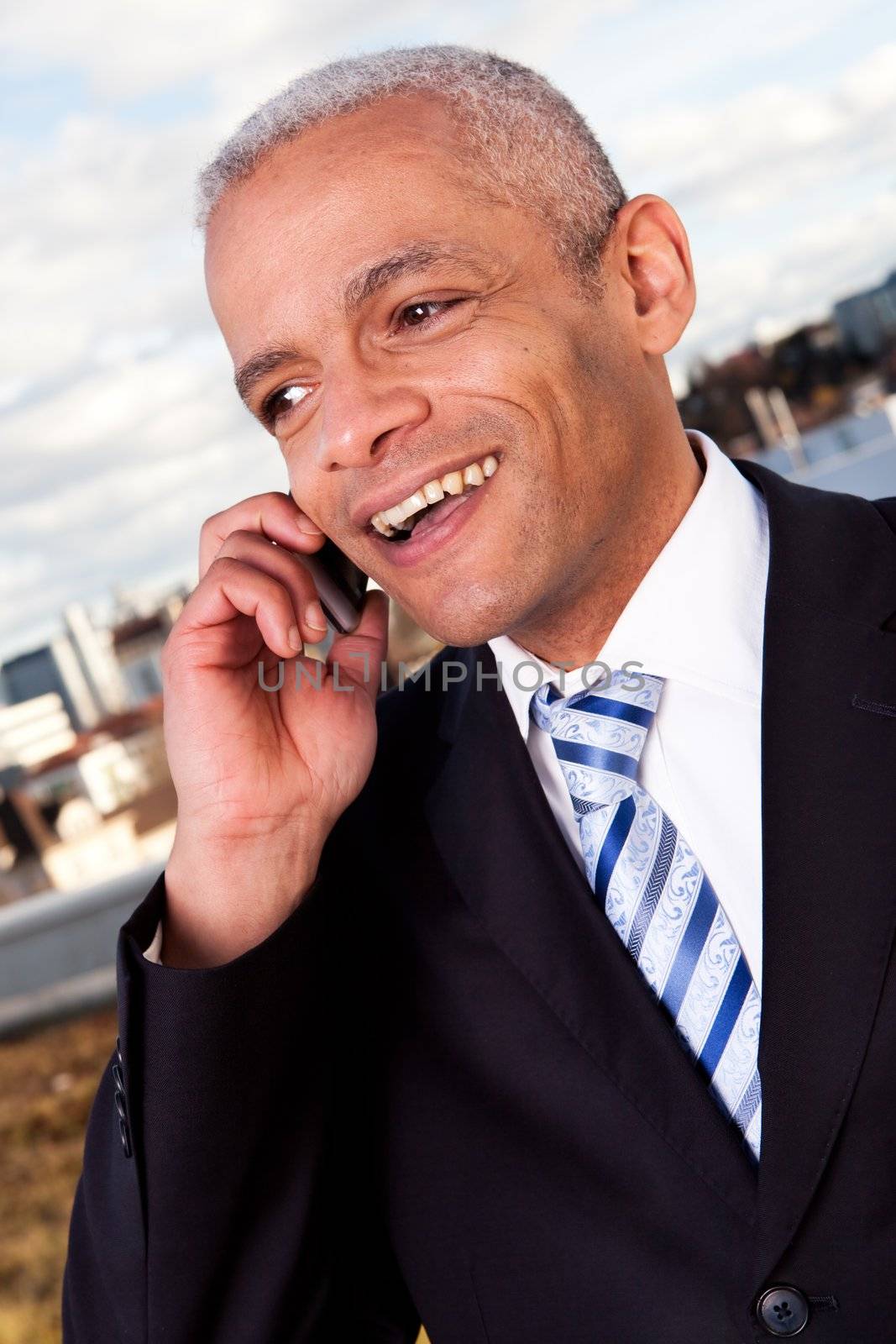 Businessman talking on cellphone outside by AndreyPopov