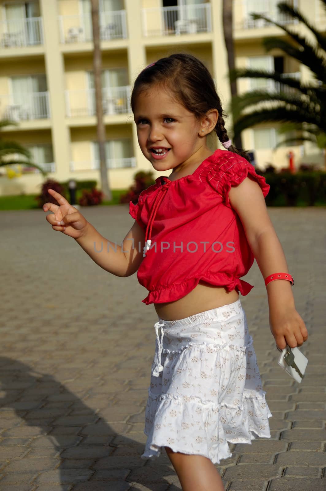 Happy child holding is holding a hotel key in one hand and pointing with the other