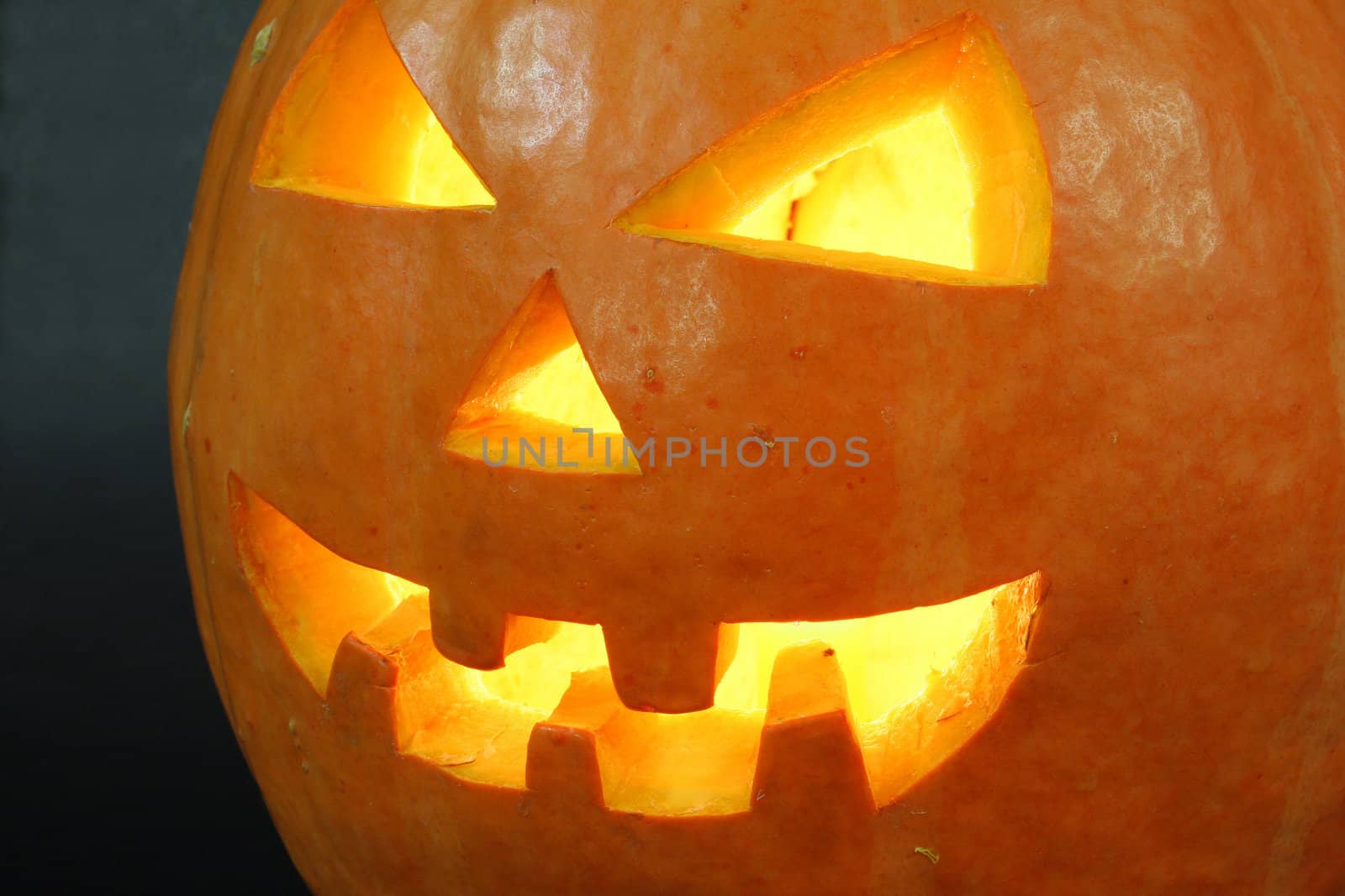 face of halloween pumpkin on black background with candle inside