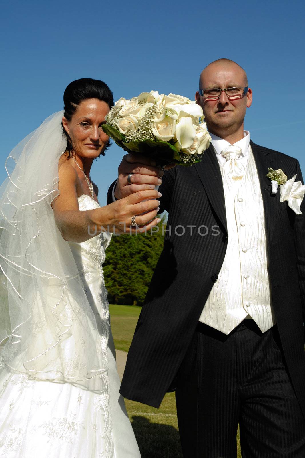 Bride and groom is holding the wedding bouquet together. Focus on the bouquet.