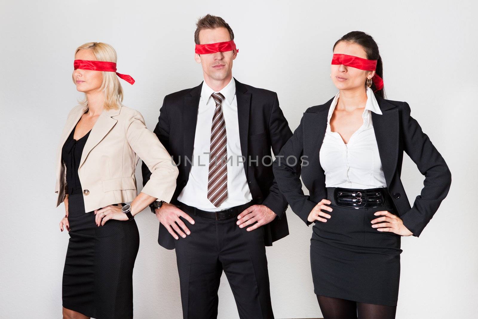 Group of disoriented businesspeople with red ribbons on eyes